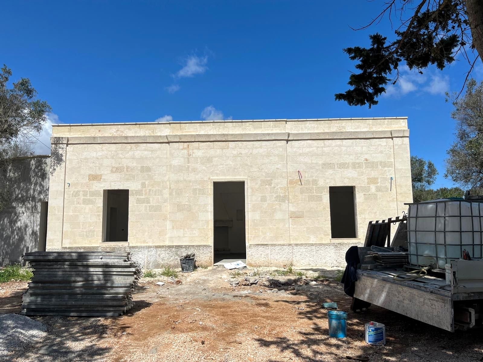The original 1800s stone facade of the Casa Andrea casale in Puglia — patinated whitewash, two wooden shutters, hand-cut openings.
