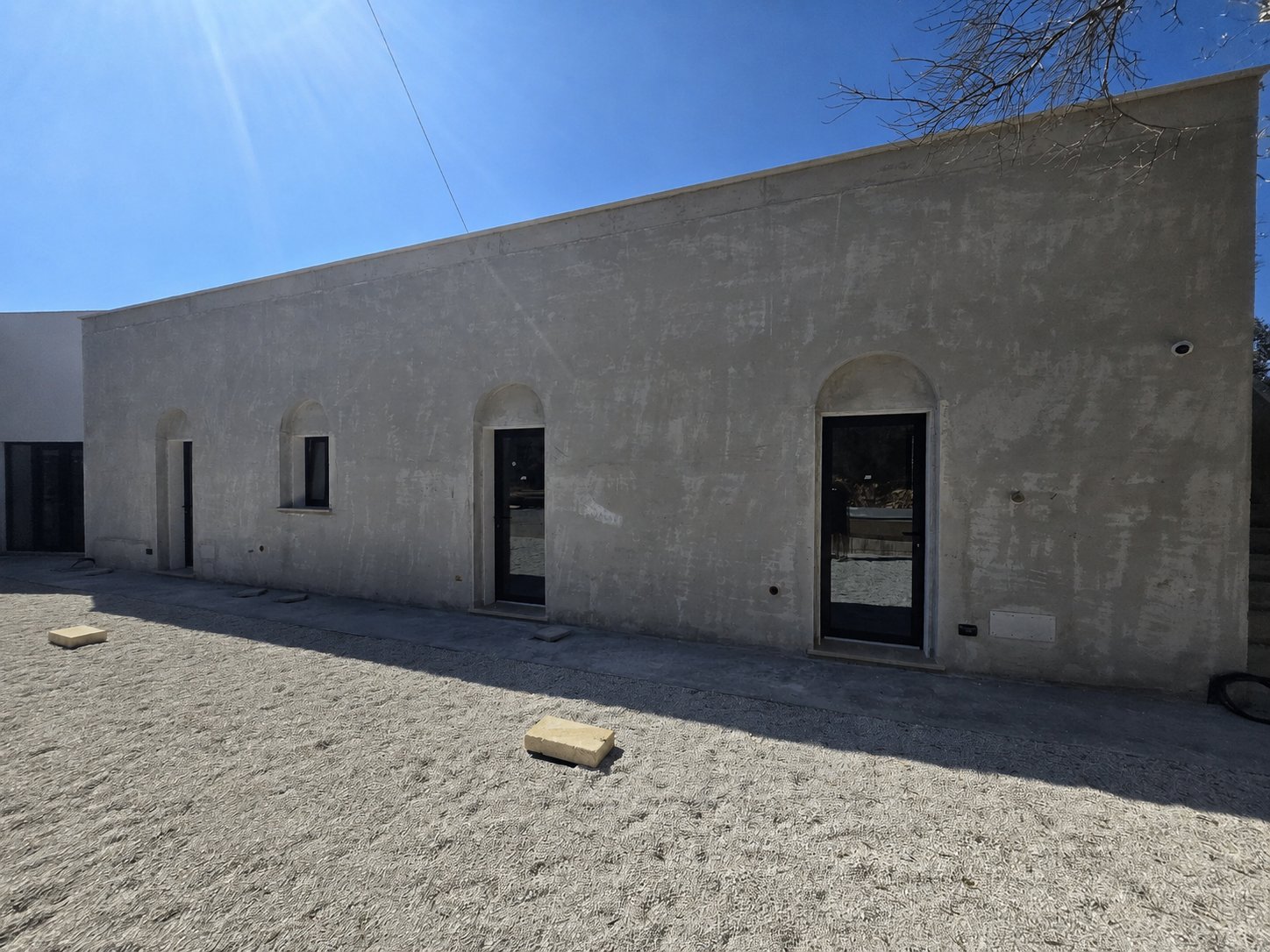 The new sleeping wing at Casa Andrea — single-storey white intonaco facade with three arched openings, one for each en-suite bedroom.
