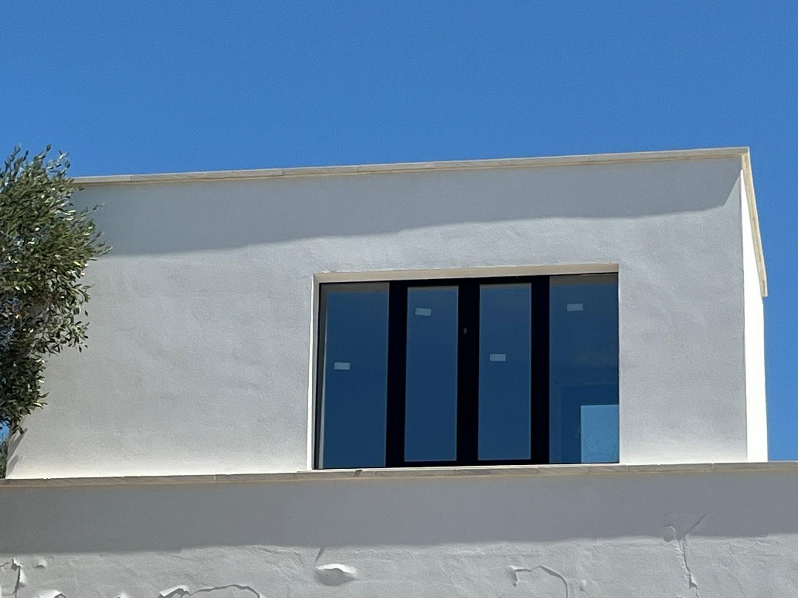 The rooftop office (bureau) of Casa Andrea above the new living wing — desk by the window, the pool visible below, the olive grove on the other side, Puglia.