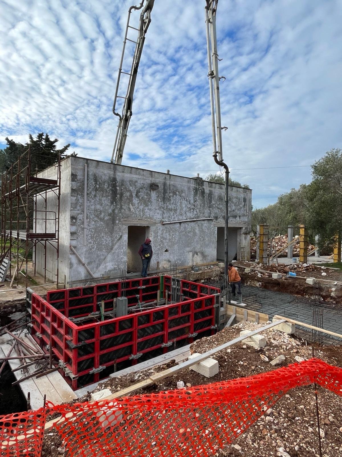 The first day of construction at Casa Andrea, February 2024 — the casale stands restored in the background, the first concrete pour is in progress, only the original wing exists so far.