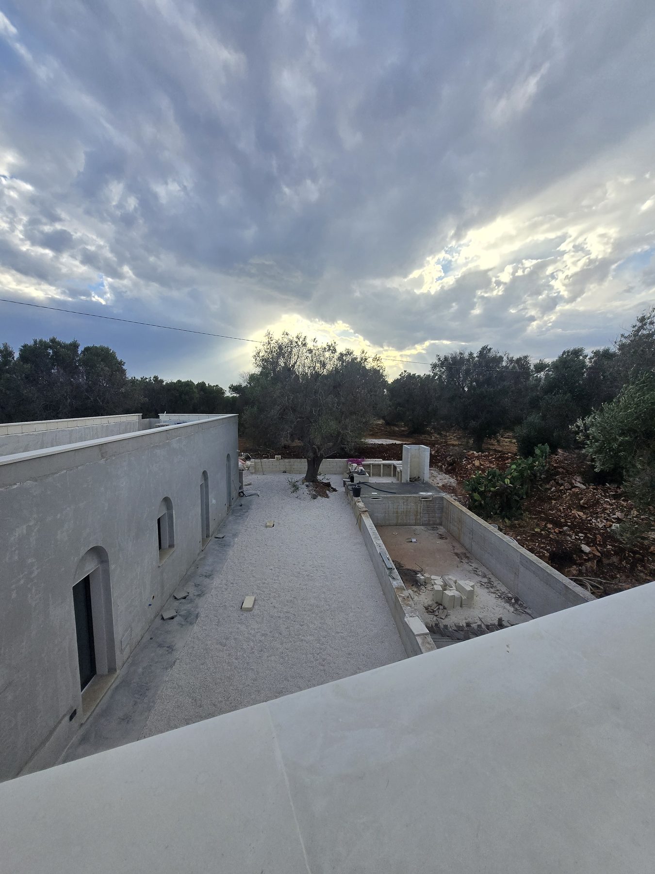 La terrasse extérieure et l'espace piscine de Casa Andrea dans les Pouilles, prenant forme à l'heure dorée près du maquis, juillet 2025.