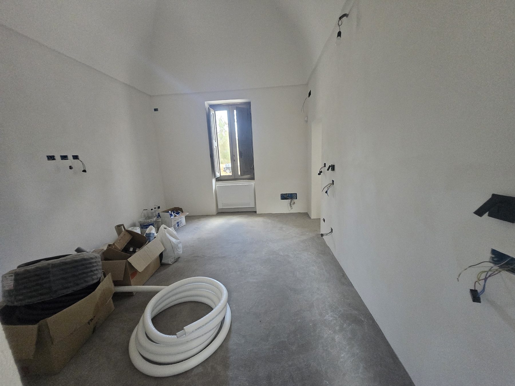 Une chambre de Casa Andrea émergeant du chantier dans les Pouilles — fenêtre cintrée d'origine, enduit à la chaux frais, juillet 2025.