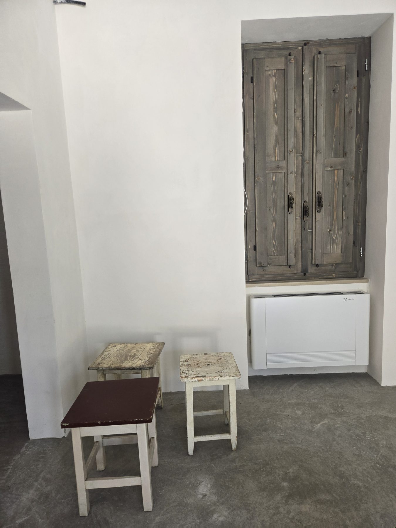 Chaises de bois peintes restaurées de la ferme originale de Casa Andrea, posées contre les murs neufs chaulés de la villa des Pouilles, août 2025.